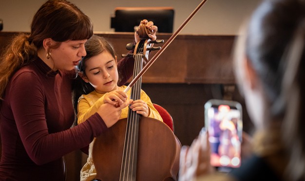 Children tries to play cello. Photo.