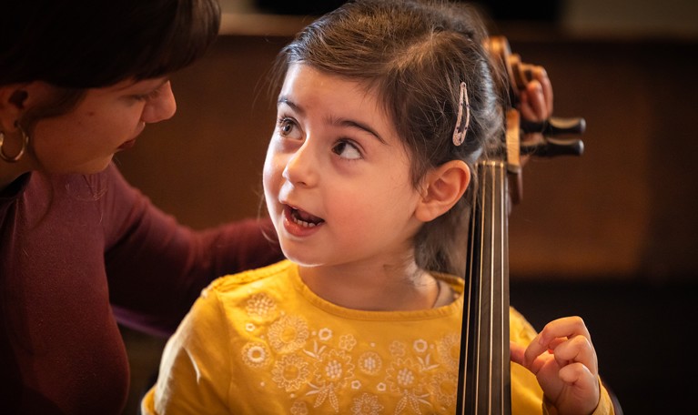 Children tries to play cello. Photo.