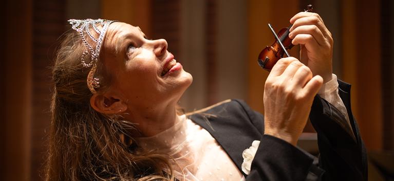 Woman holding a very small violin. Photography.