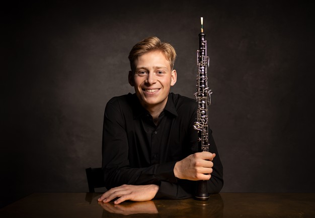 Porträttbild på en leende man med oboe. Fotografi..