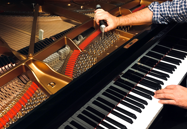 Person som stämmer ett piano och justerar klangen. Fotografi.