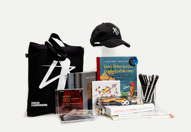 Different items from the shop - a black textile bag, CDs, books and a black cap. Photo.
