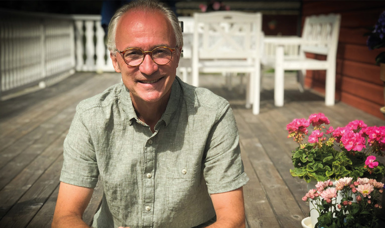 Leende farbror som sitter på en trappa. Fotografi.