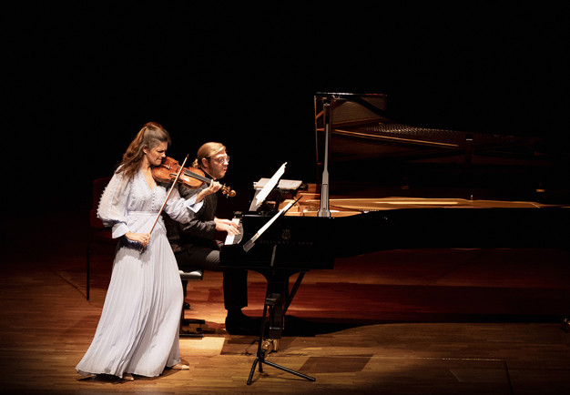 Kvinna som spelar violin och man spelar piano. Fotografi.