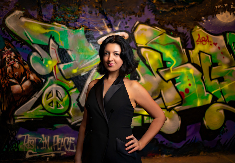 Kvinna som står mot en graffitivägg. Fotografi.