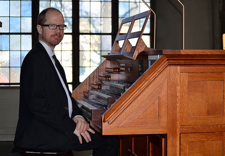 Närbild på man vid orgel. Fotografi.