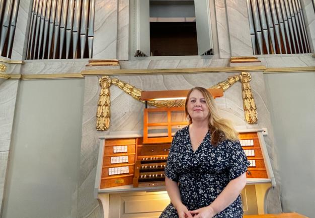 Kvinna som sitter framför en orgel. Fotografi.