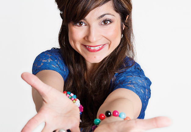 Close-up of Ayla Kabaca, looking into the camera and reaching out her arms to the viewer. Photography