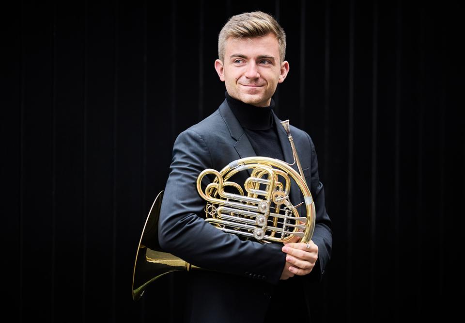 Young man holding a french horn. 