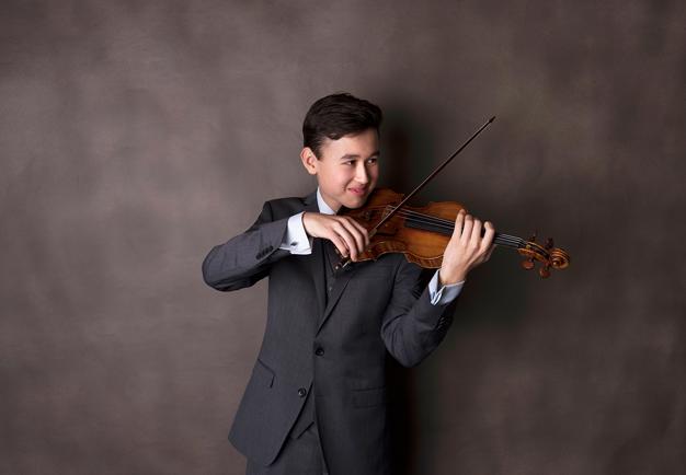 Ung man som spelar violin. Fotografi.