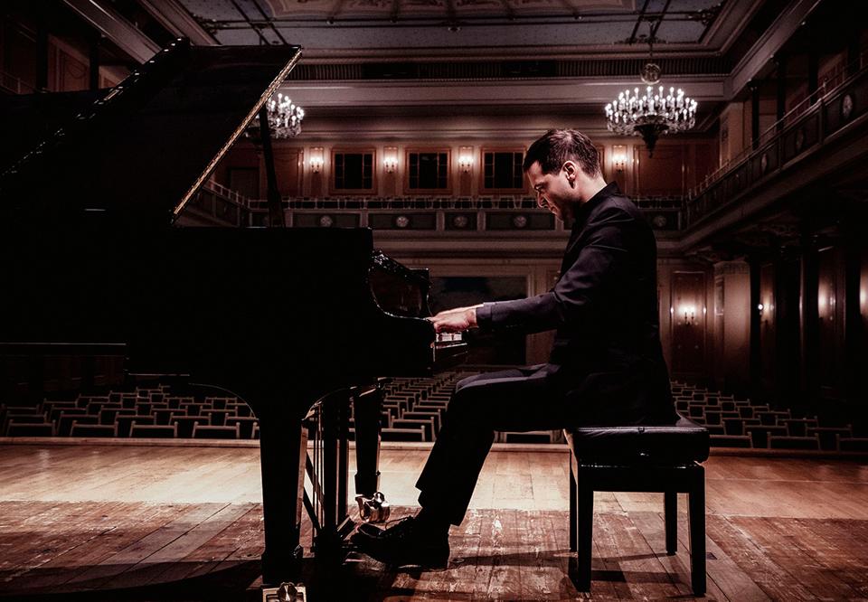 Francesco is playing on his piano at a concerthall. Photo.