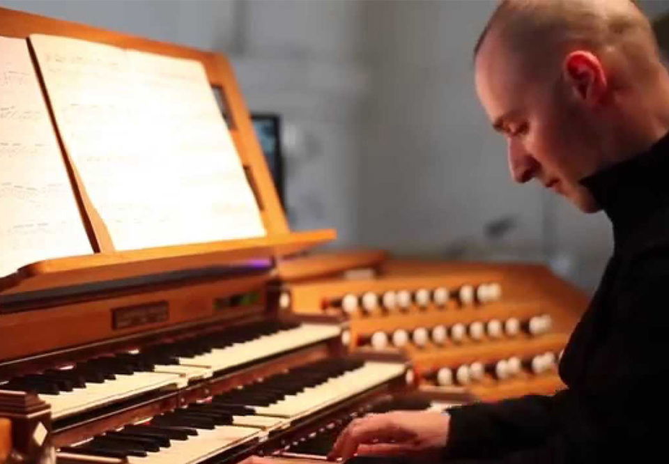 Man som sitter och spelar på en orgel.