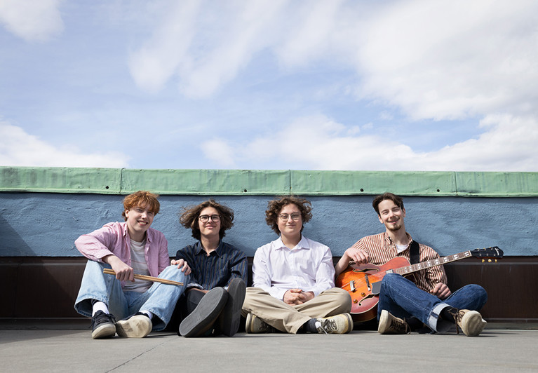 Fyra musiker som sitter på taket. Fotografi.