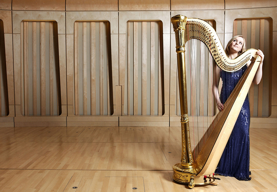 Kvinna som tår bredvid en harpa. Fotografi.