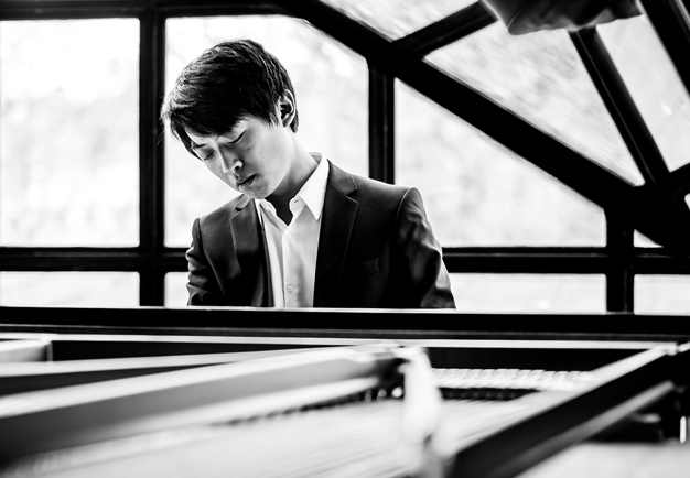Young guy by a piano. Black and white photo.