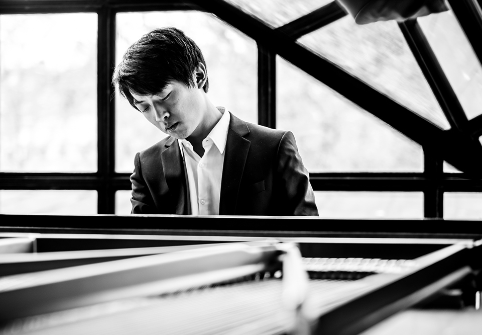 Svarty vit bild på ung kille som spelar piano. Fotografi.