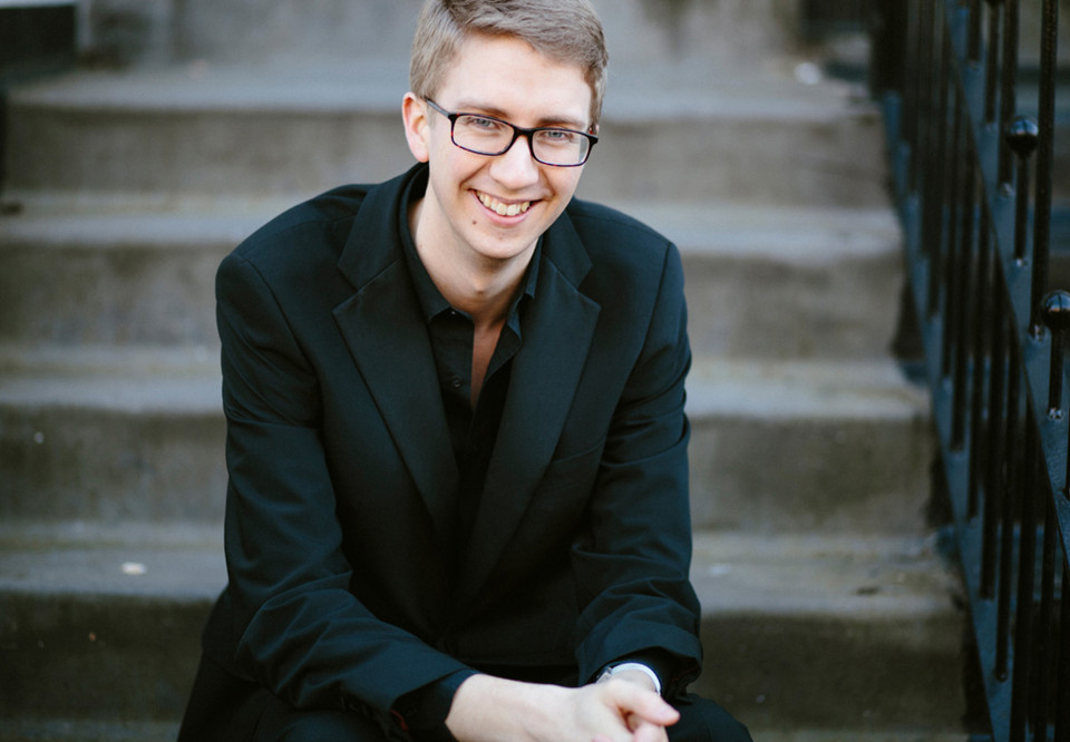 Ung kille som lutar sig framåt sittandes på en trappa. Fotografi.