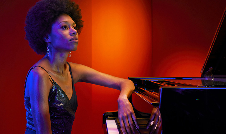 Woman sitting beside a piano. Photo.