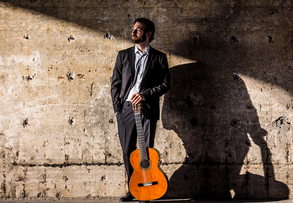 Man som står med sin gitarr. Fotografi.