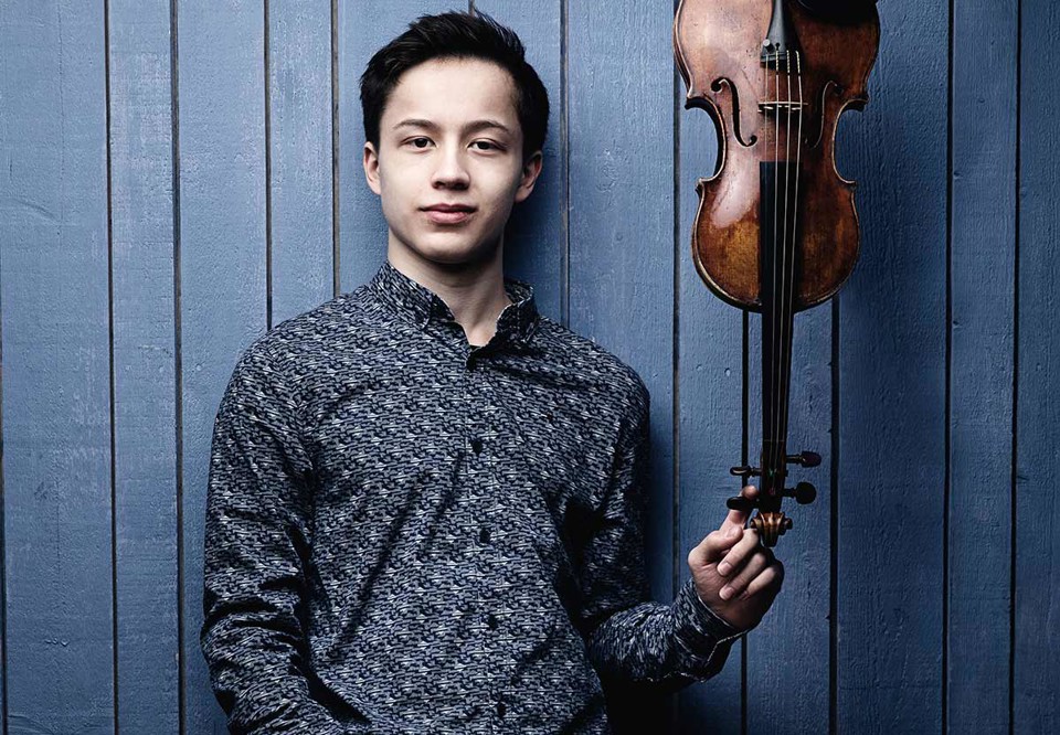 Young guy holding his violin. Photo.
