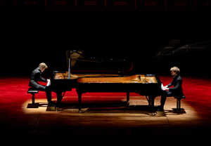 Två personer som spelar piano. Fotografi