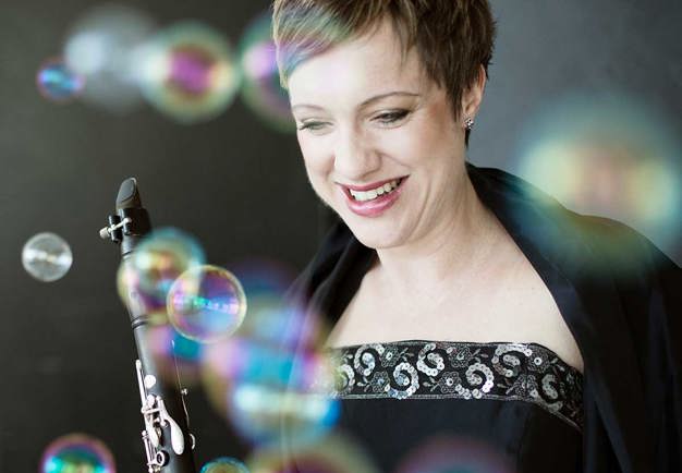 Close up of the musician holding her clarinet and looking downwards. Photo.