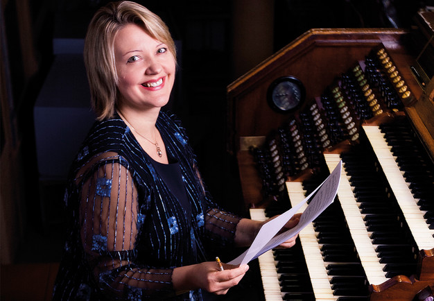 Leende organist med partitur i handen. Ligita Sneibe. Fotografi.