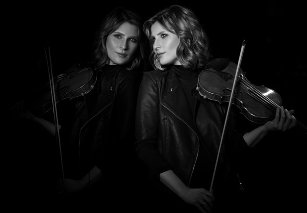 Kvinna som håller i en violin. Fotografi.