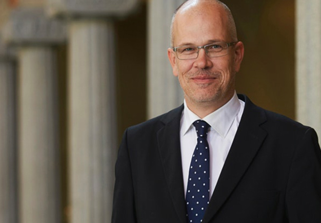 Man standing with a black suite. Photo.