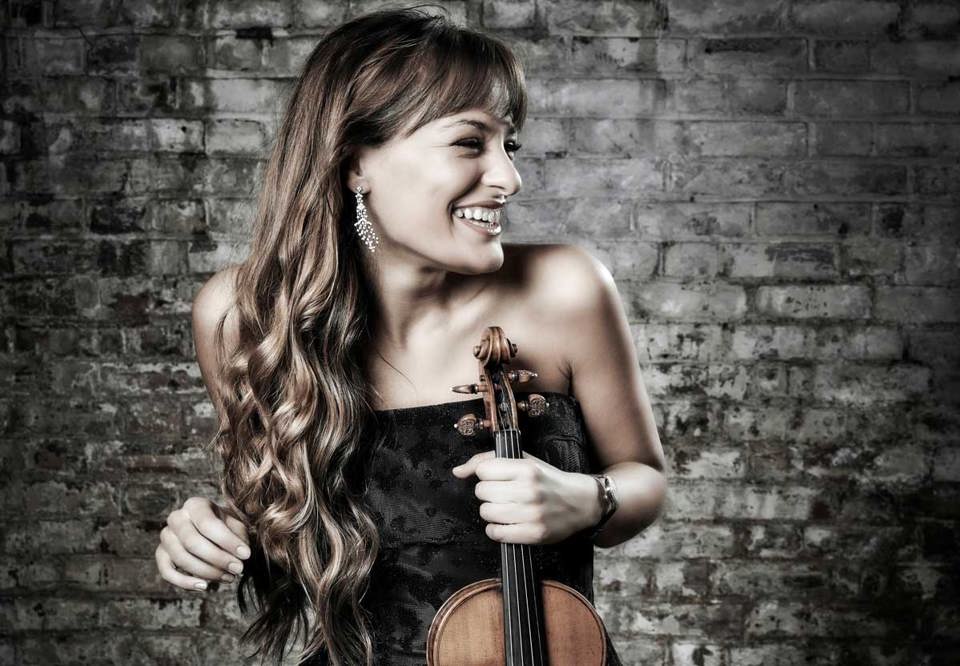 Photo of a woman standing with her violin. 