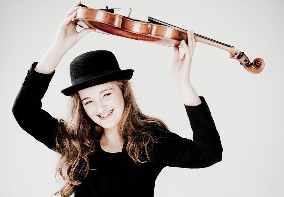 Ung tjej som håller violinen ovanför huvudet. Fotografi.