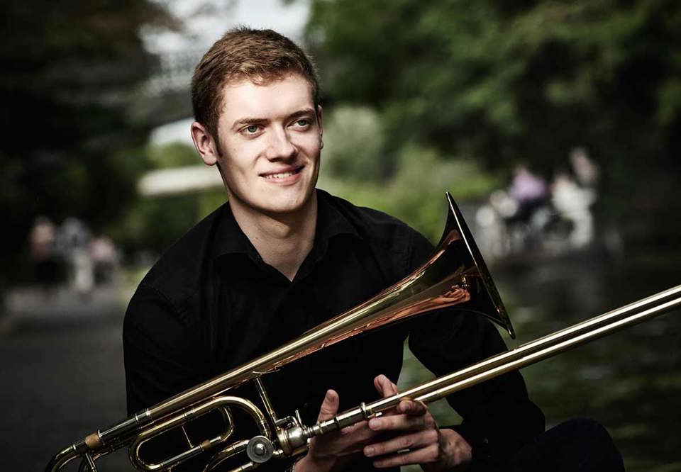 Young guy with his trumpet in his knee. Photo.