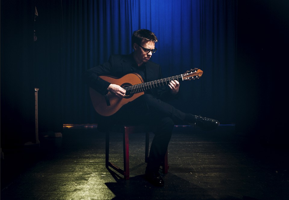 Man som spelar gitarr. Fotografi.