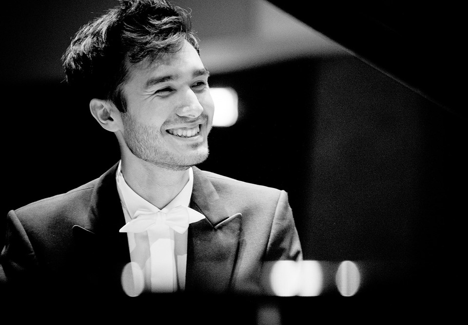 Man som sitter vid ett piano. Fotografi
