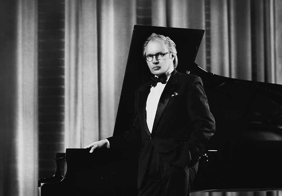 Black and white photo of a man infront of the piano.