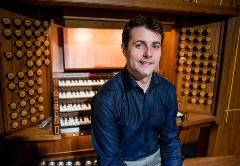 Organist Ulf Norberg sitting by the organ at Konserthuset looking into the camera. Photography.