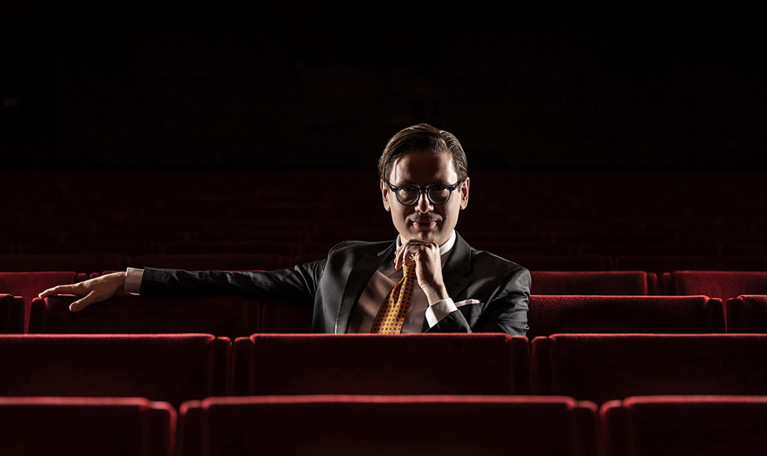 Man som sitter bland fåtöljer. Fotografi