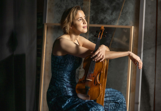 Kvinna med violin i handen. Fotografi.