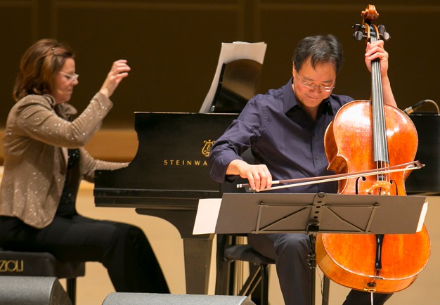 Man sitting with his cello. Photo.
