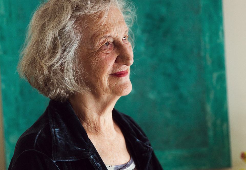 Äldre gråhårig kvinna mot grön bakgrund. Fotografi.